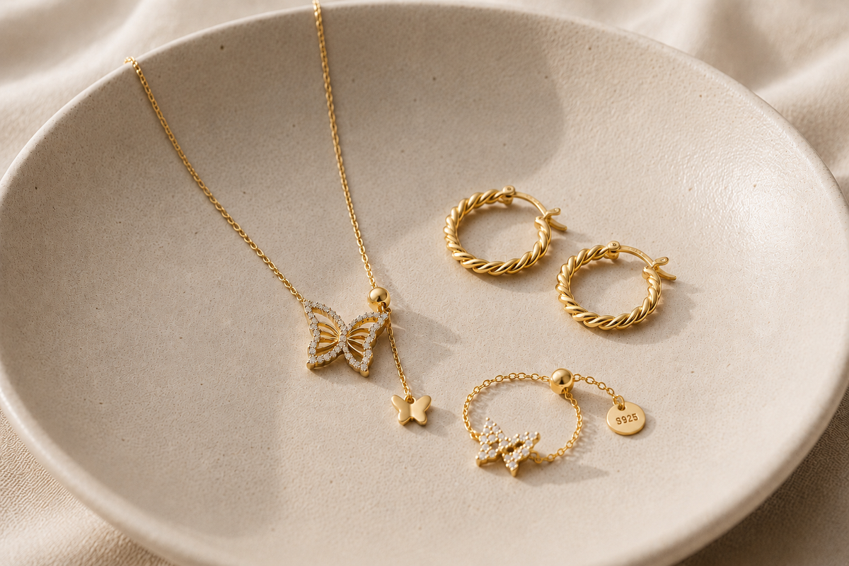 Gold-coloured earrings and necklace arranged on a white plate
