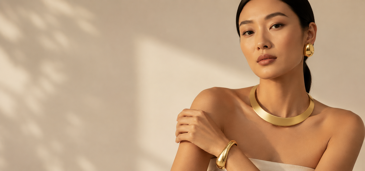 Woman wearing layered gold necklaces and a wide gold cuff