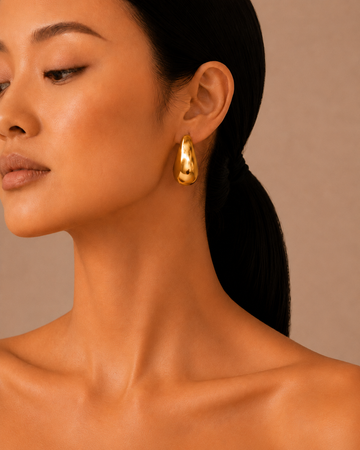 Gold-coloured drop earrings worn on the ear