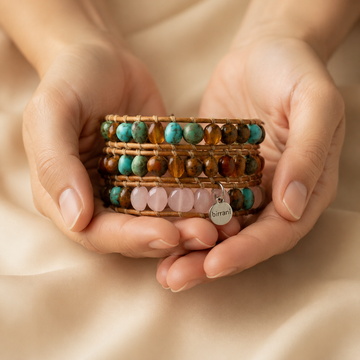 Hands holding several beaded gemstone bracelets