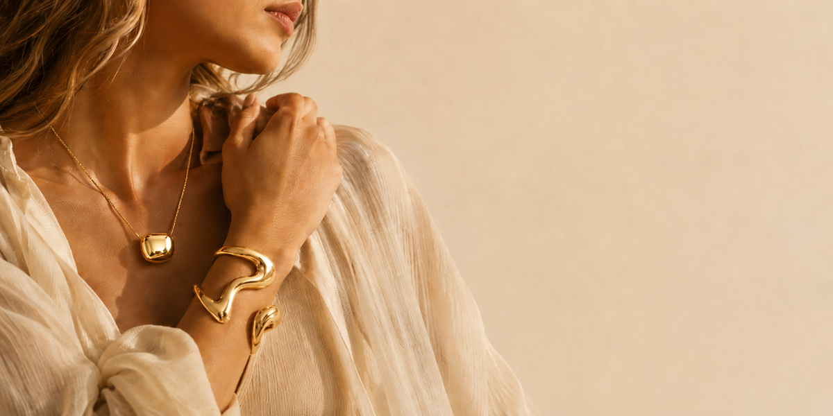 Woman wearing polished gold jewellery with a cream blouse