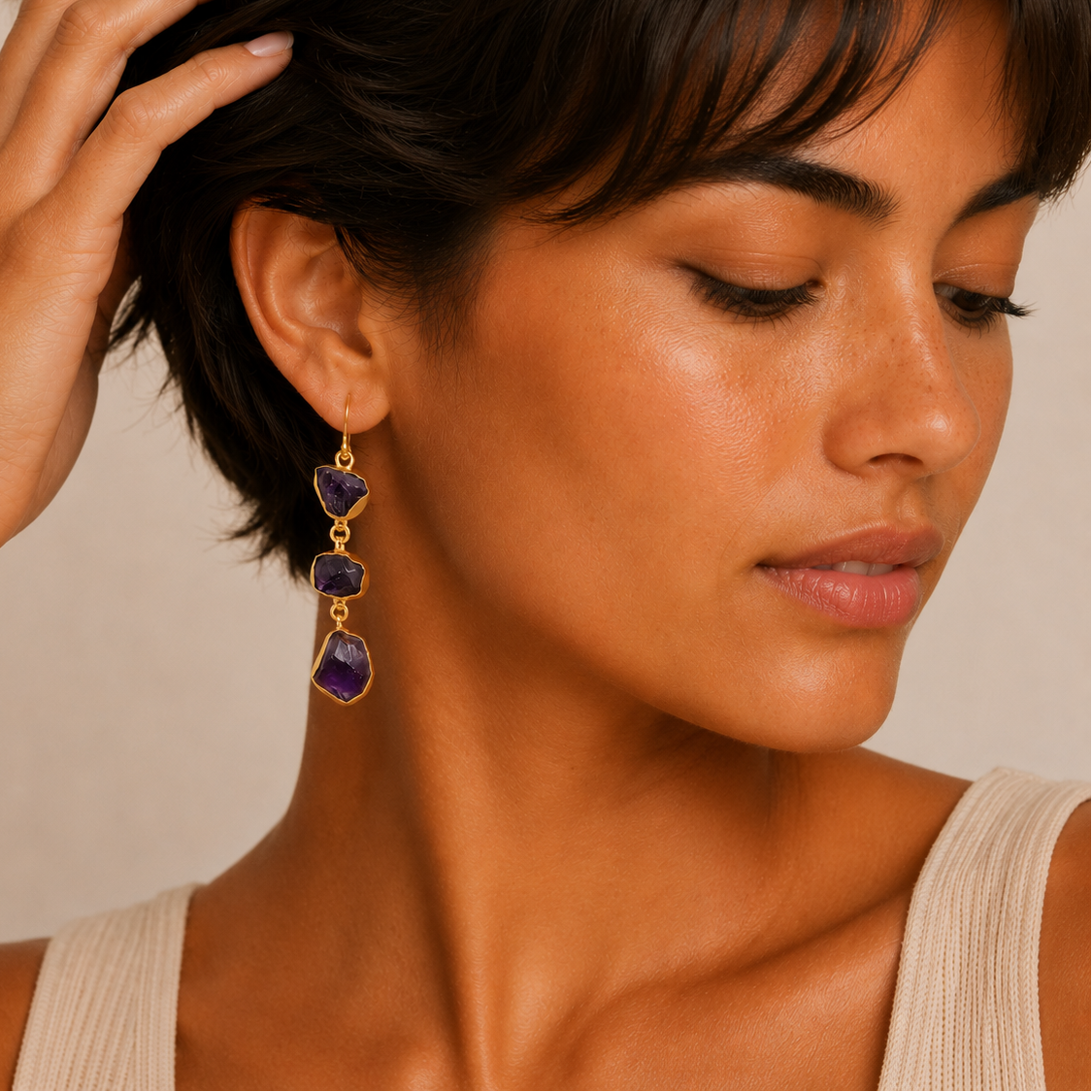 Amethyst Fall Earrings worn on the ear, with three irregular purple stones on each drop
