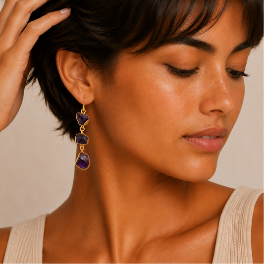 Amethyst Fall Earrings worn on the ear, with three irregular purple stones on each drop