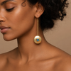 Apatite Disc Earrings worn on the ear, with long gold-coloured stems and round disc drops with blue centres