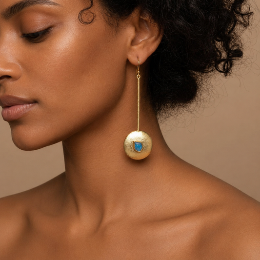 Apatite Disc Earrings worn on the ear, with long gold-coloured stems and round disc drops with blue centres