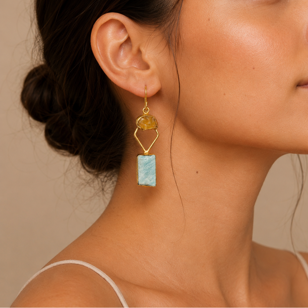 Citrine Tide Earrings worn on the ear, with pale blue rectangular stones and geometric gold-coloured frames