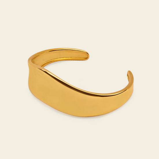 Crest Band Cuff with a broad polished band with a wavy edge in gold finish