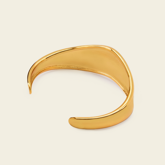 Crest Band Cuff with a broad polished band with a wavy edge in gold finish