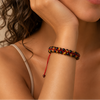 Crimson Thread Bracelet worn on the wrist, with black beads woven onto red cord