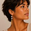 Crystal Cascade Earrings worn on the ear, with pale stone accents and long gold-coloured chain tassels