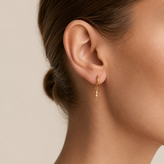 Fine Strike Earrings worn on the ear in gold finish
