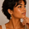 Golden Axis Earrings worn on the ear, with elongated open frames with pale stone accents