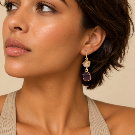 Golden Dusk Earrings worn on the ear, with pale stone tops and dark purple stone drops