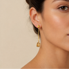 Golden Ease Earrings worn on the ear, with slender gold-coloured stems with small amber-coloured drops