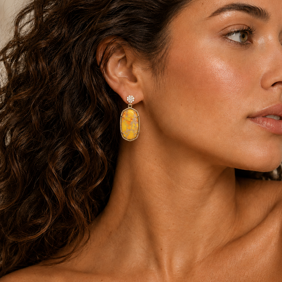 Golden Field Earrings worn on the ear, with yellow and orange patterned rectangular stone drops