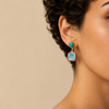 Harbour Ember Earrings worn on the ear, with turquoise-coloured stone drops edged in red and gold colours