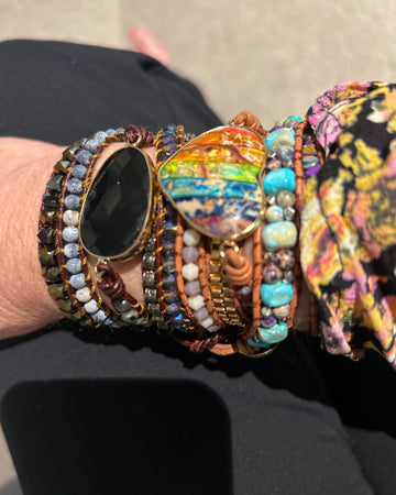 Layered multicoloured bracelets worn with a dark round watch