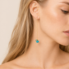 Long Drift Earrings worn on the ear, with long fine gold-coloured hooks and small blue stone drops