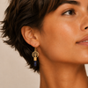 Midnight Roots Earrings worn on the ear, with round gold-coloured motifs above slim blue stone drops