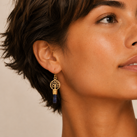 Midnight Roots Earrings worn on the ear, with round gold-coloured motifs above slim blue stone drops