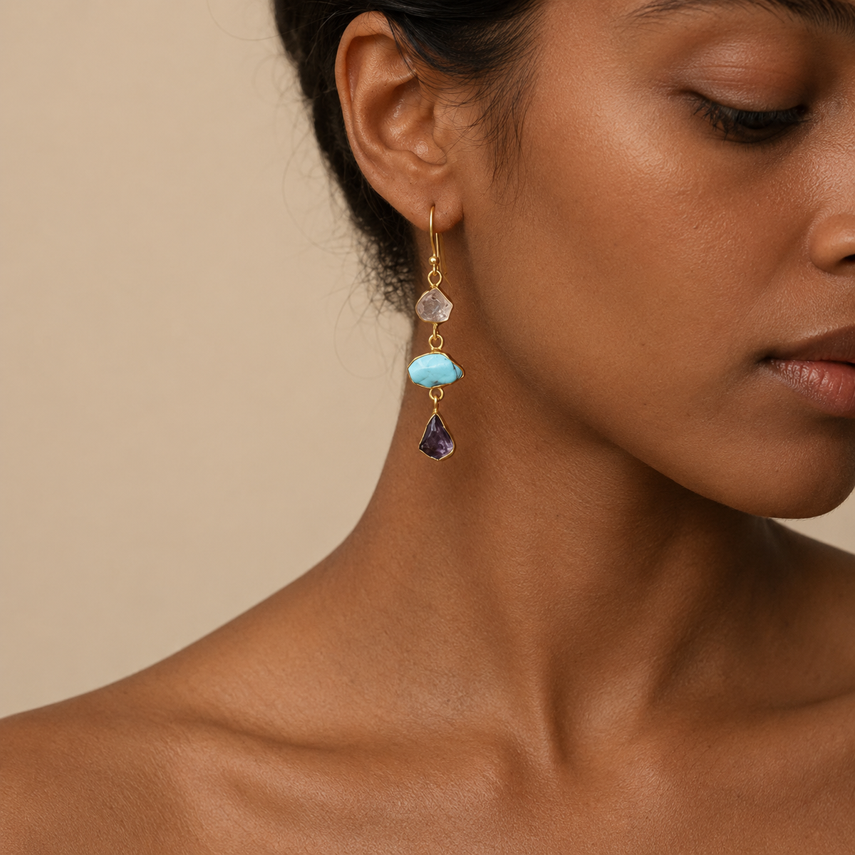 Ocean Muse Earrings worn on the ear, with pale and turquoise-coloured stones with dark teardrop drops