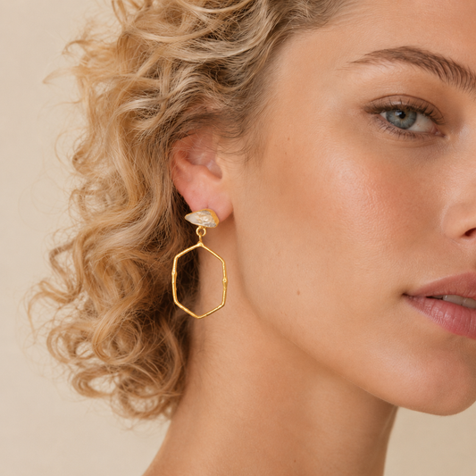 Open Halo Earrings worn on the ear, with open hexagonal drops beneath pale stone tops