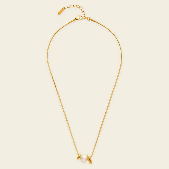 Pearl Embrace Necklace with a central pearl framed by curved metal details in gold finish