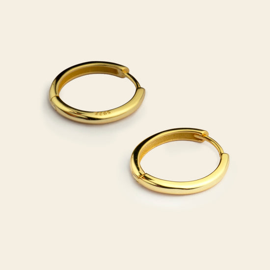 Quiet Arc Earrings with smooth oval hoops in gold finish