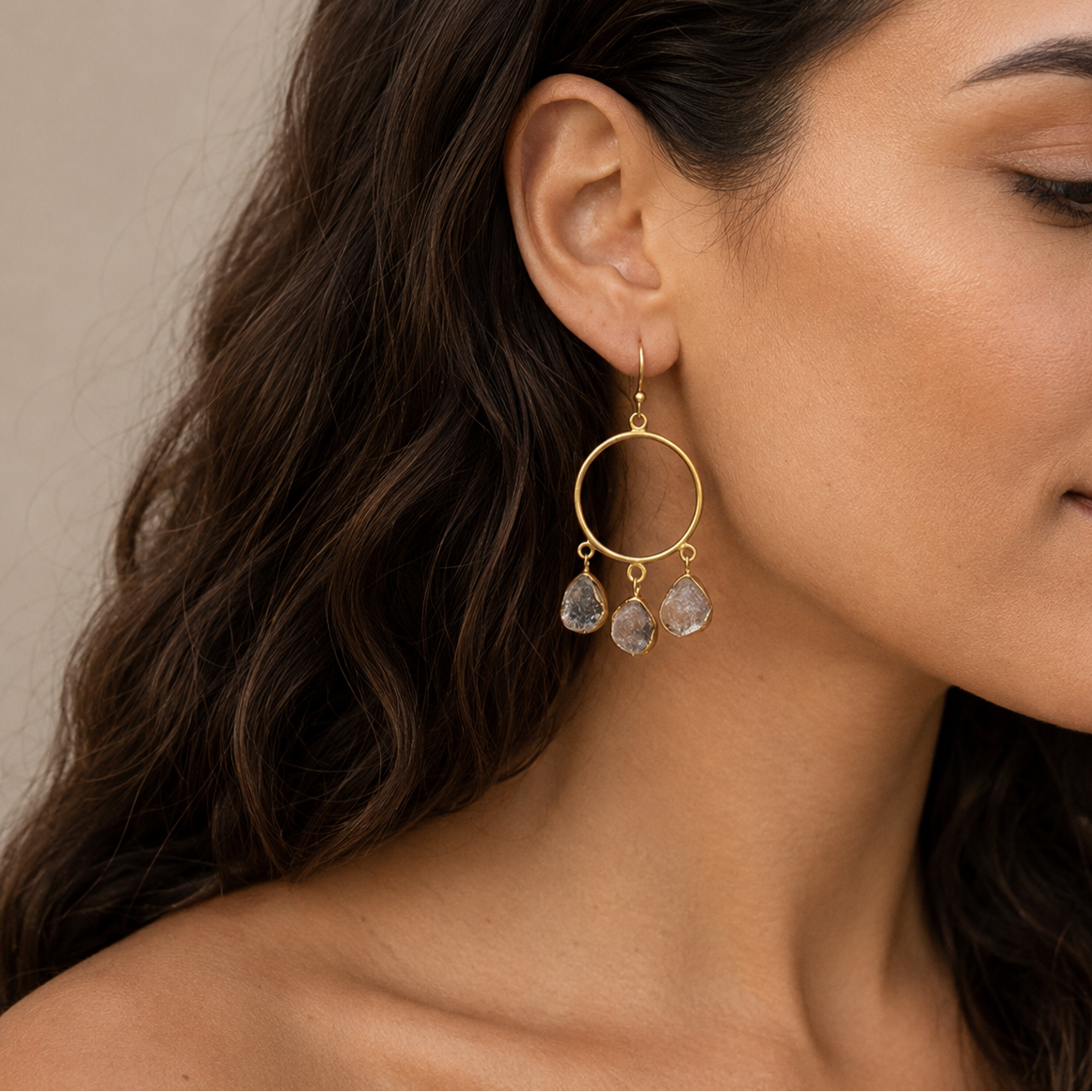 Raw Balance Earrings worn on the ear, with open circular frames and three pale stone drops
