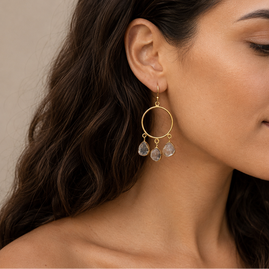 Raw Balance Earrings worn on the ear, with open circular frames and three pale stone drops