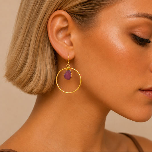 Ruby Hoop Earrings worn on the ear, with open gold-coloured circles and purple stone drops