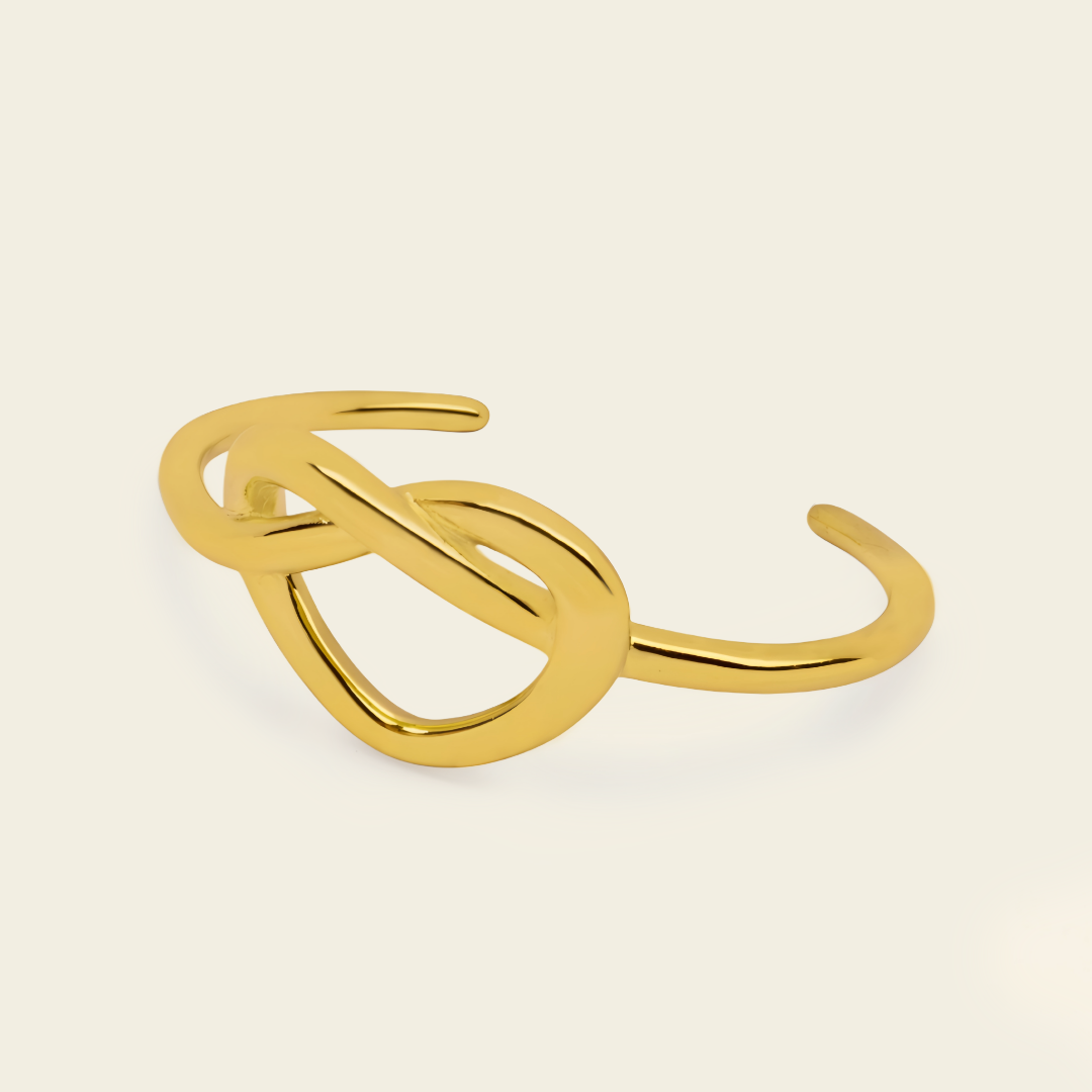 Sculpted Knot Cuff with an open band with a central sculpted knot in gold finish
