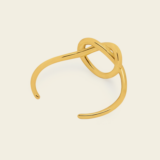 Sculpted Knot Cuff with an open band with a central sculpted knot in gold finish