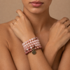 Soft Bloom Necklace worn wrapped around the wrist, with pink round stone beads and a small round charm