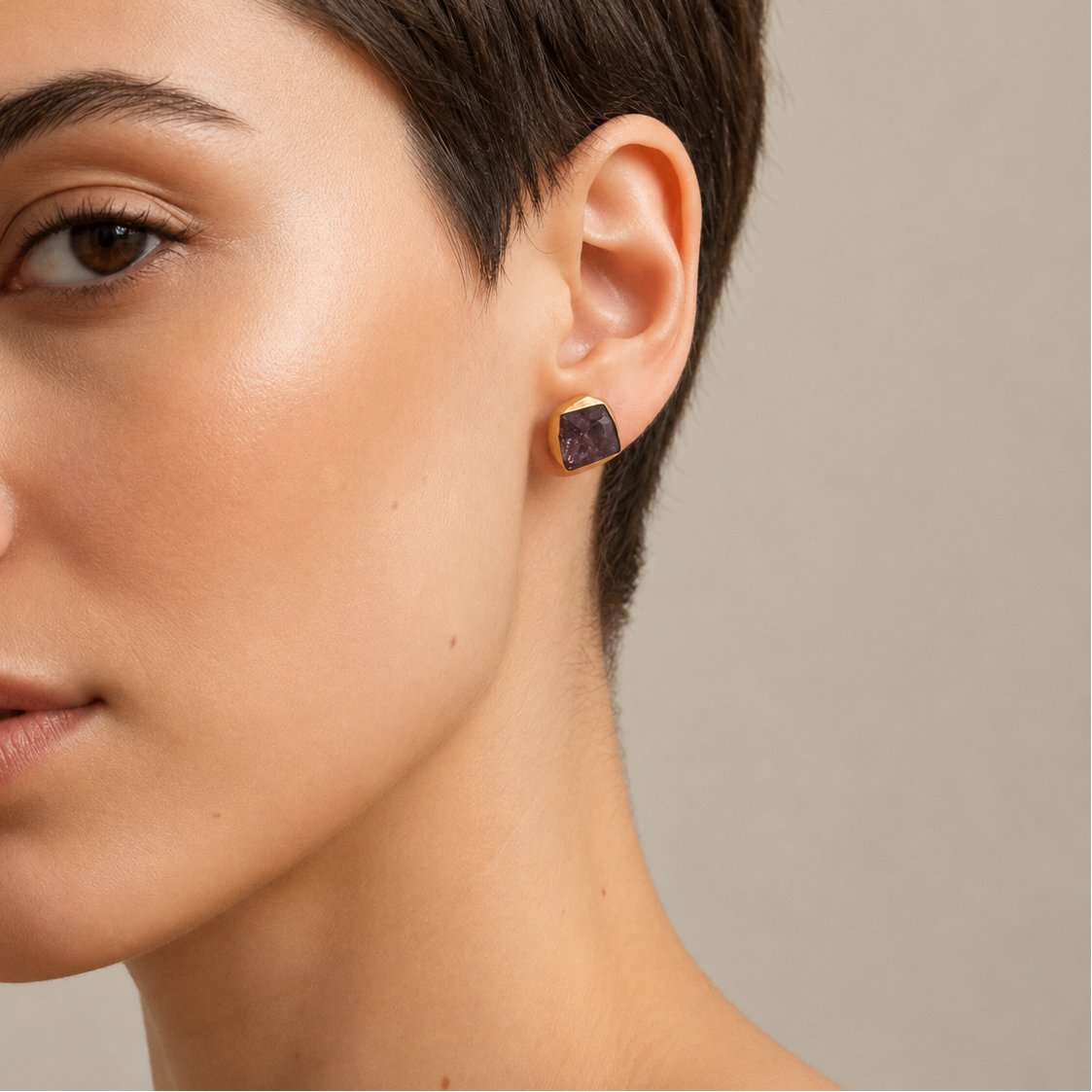 Still Core Earrings worn on the ear, with irregular purple stone studs with gold-coloured edges