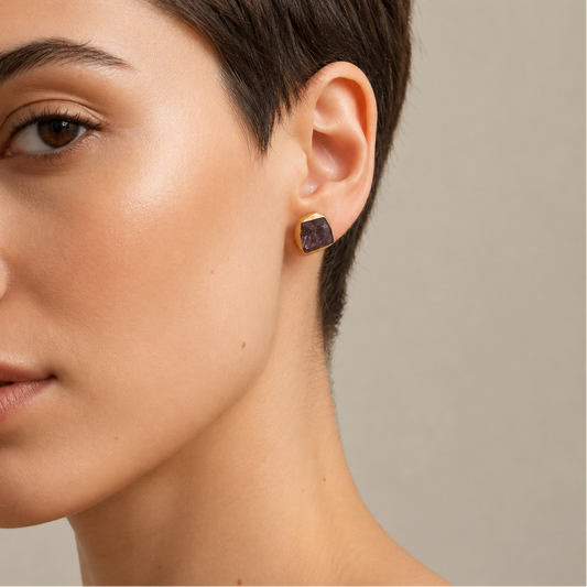 Still Core Earrings worn on the ear, with irregular purple stone studs with gold-coloured edges