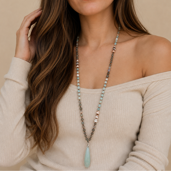 Stillwater Thread Necklace worn at the neckline, with pale beads and an elongated pale pendant