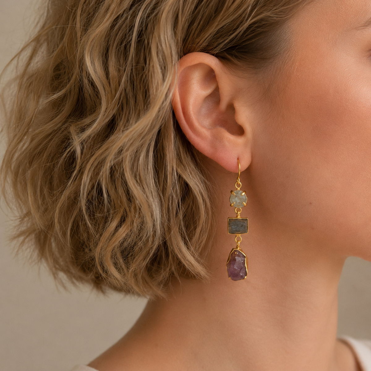 Stone Alignment Earrings worn on the ear, with a vertical arrangement of pale, blue and purple stones