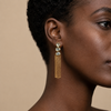 Sunlit Tassel Earrings worn on the ear, with pale stone tops and long gold-coloured chain tassels