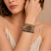 Time Spiral Bracelet worn on the wrist, with layered earth-toned beads and pale cord