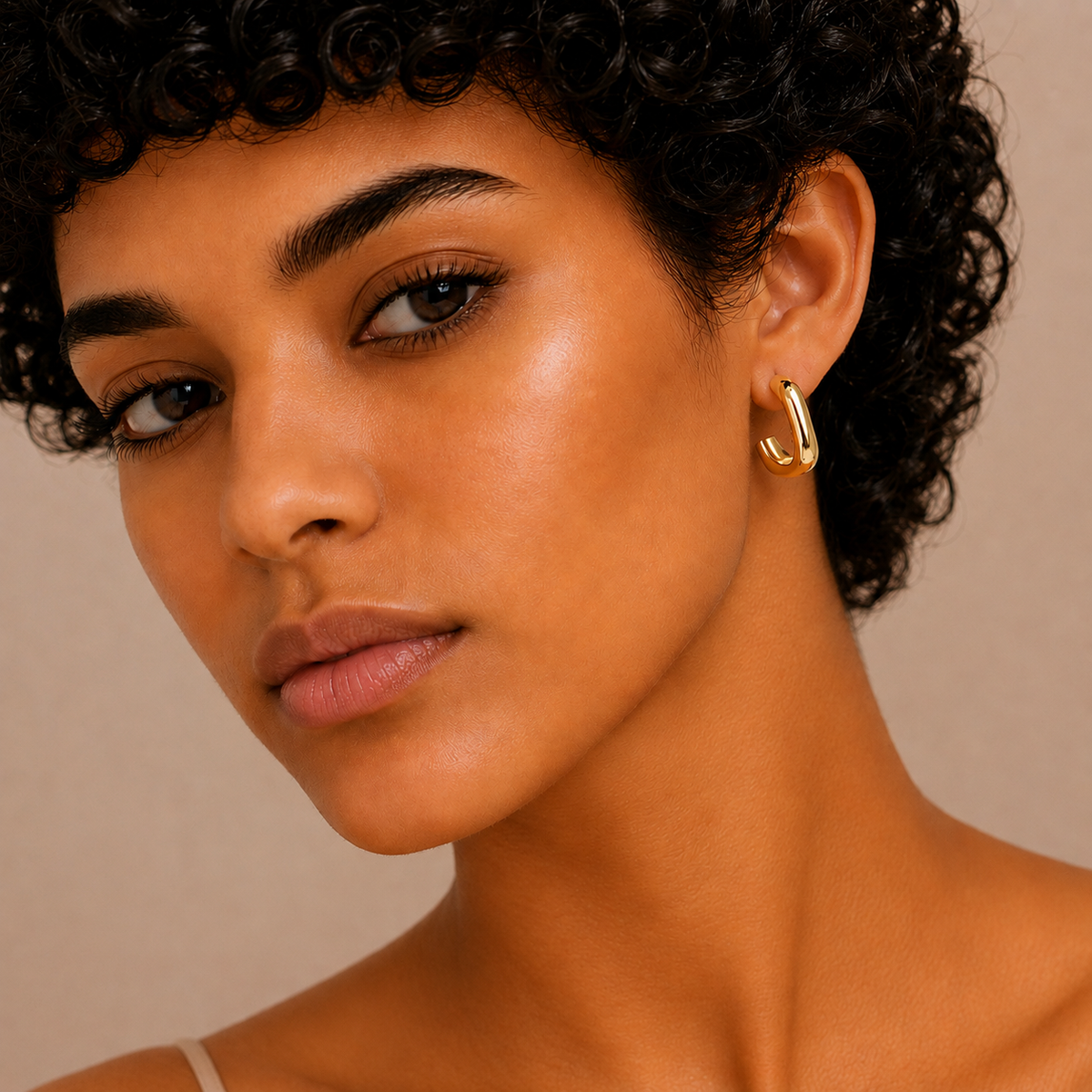 Twisted Ribbon Earrings worn on the ear in gold finish