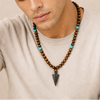 Vector Calm Necklace worn at the neckline, with brown stone beads and a pointed metal pendant
